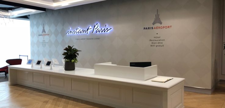 a white reception desk with a plant and a sign on the wall