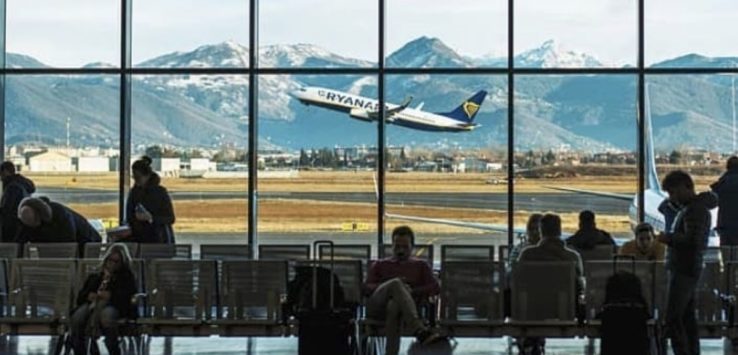 a group of people sitting in chairs in a waiting room with a plane flying in the sky