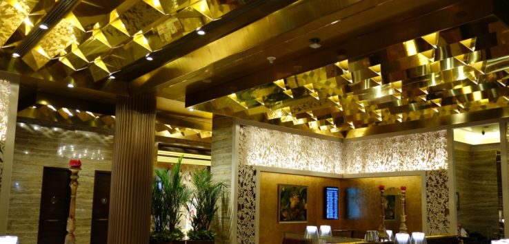 a room with a gold ceiling and a table with a lamp