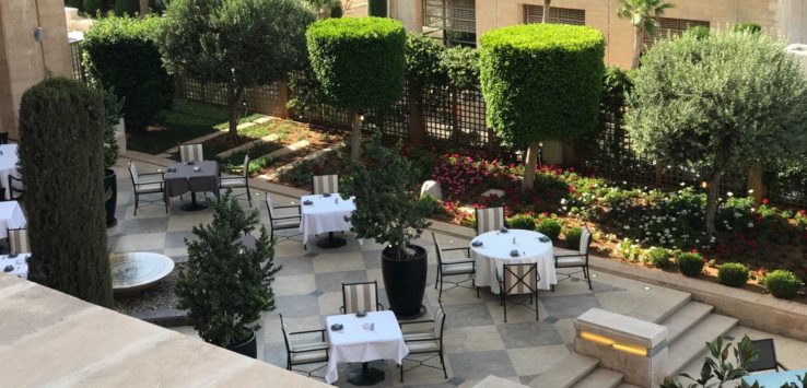 a patio with tables and chairs and bushes