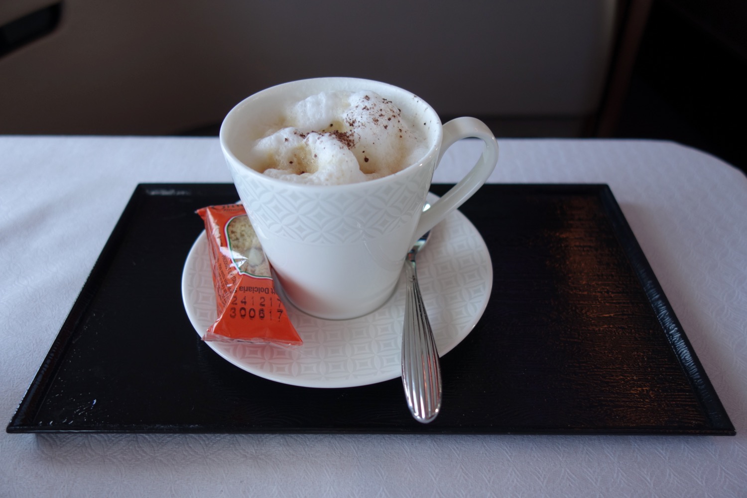 a cup of coffee with a spoon and a packet on a tray
