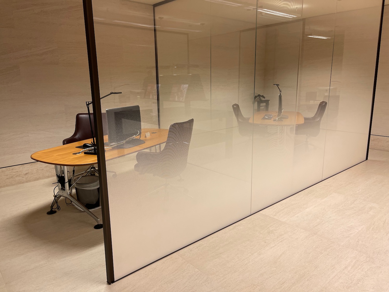 a glass wall with a desk and chairs