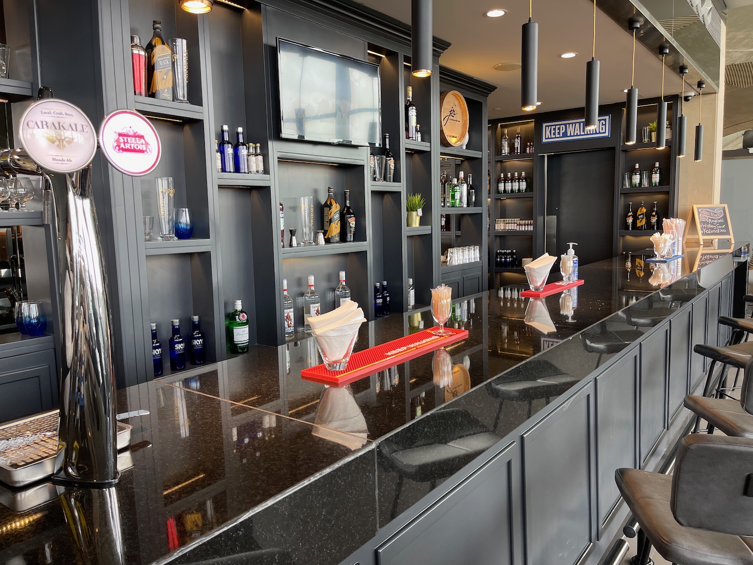 a bar with a black counter and shelves with bottles