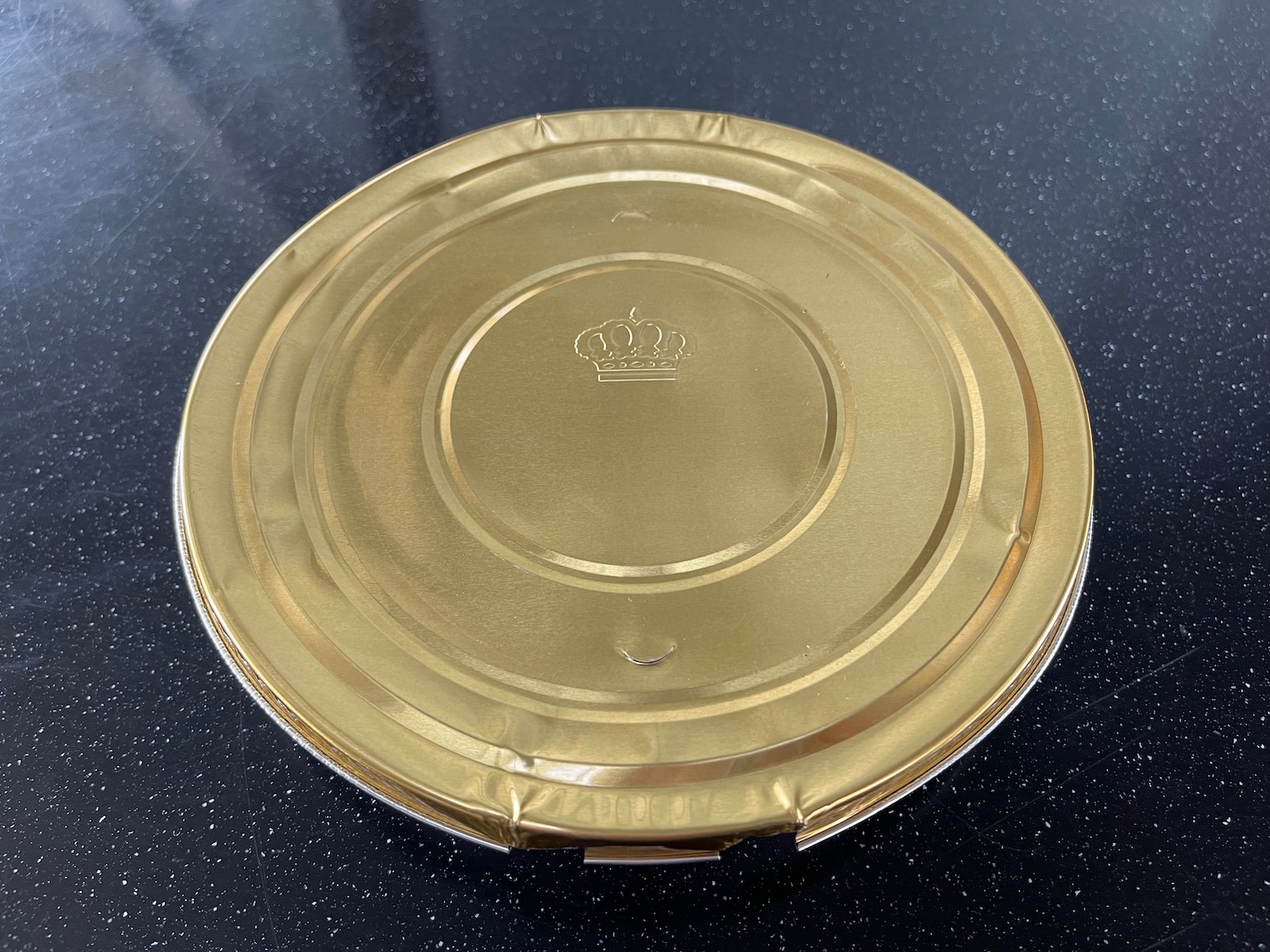 a round gold container with a crown on it