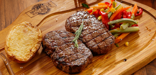 a steak and vegetables on a wooden board