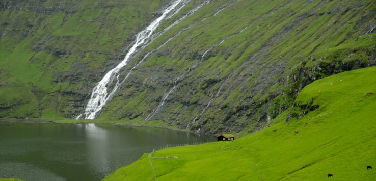 a waterfall over a green hill