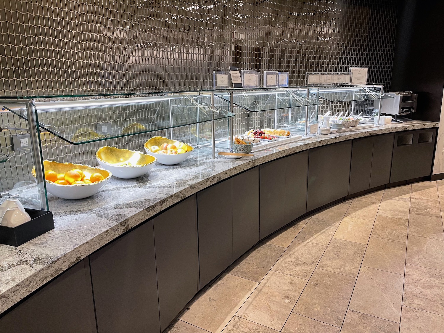 a buffet line with bowls of fruit