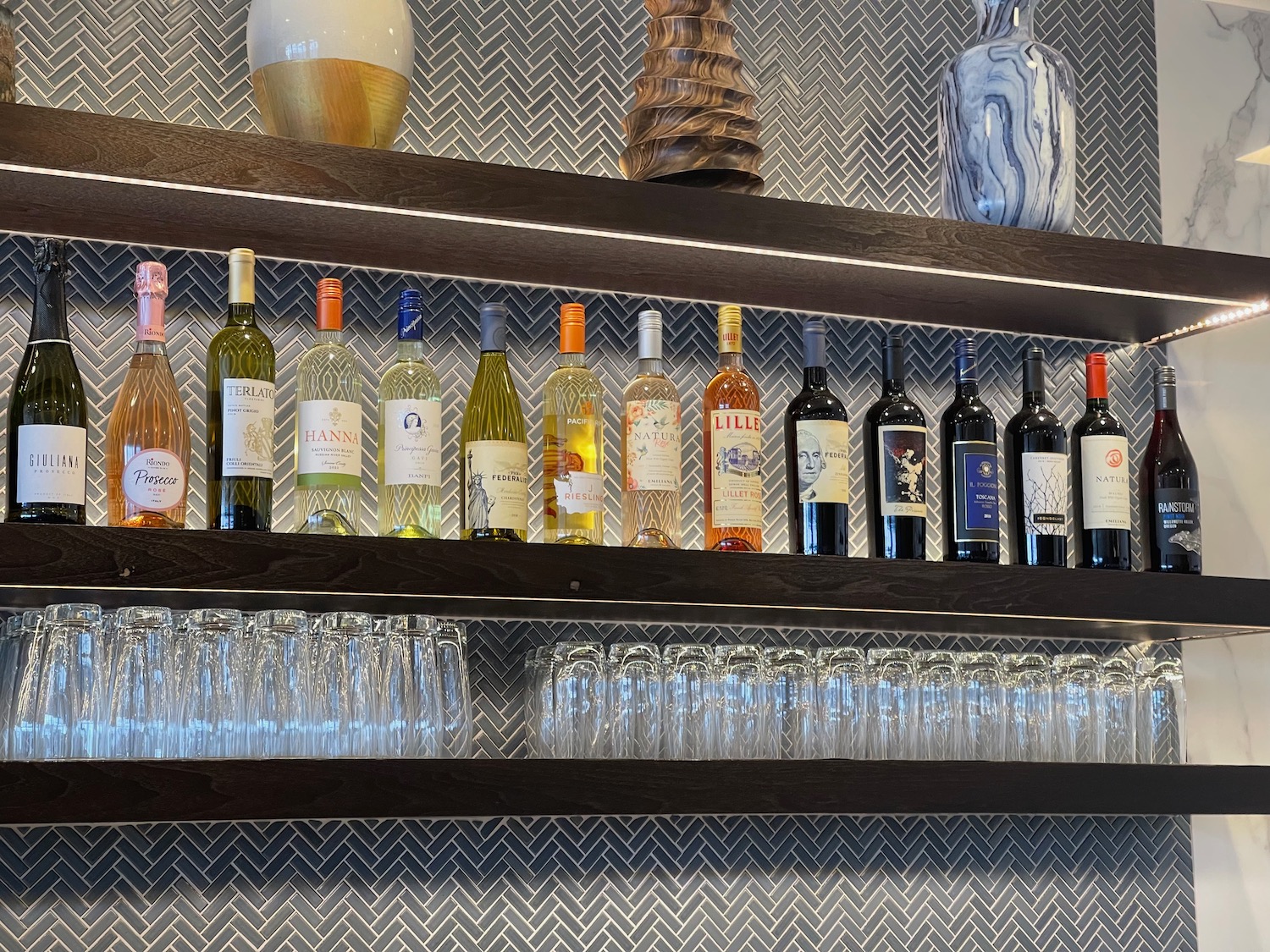 a shelf with wine bottles and glasses