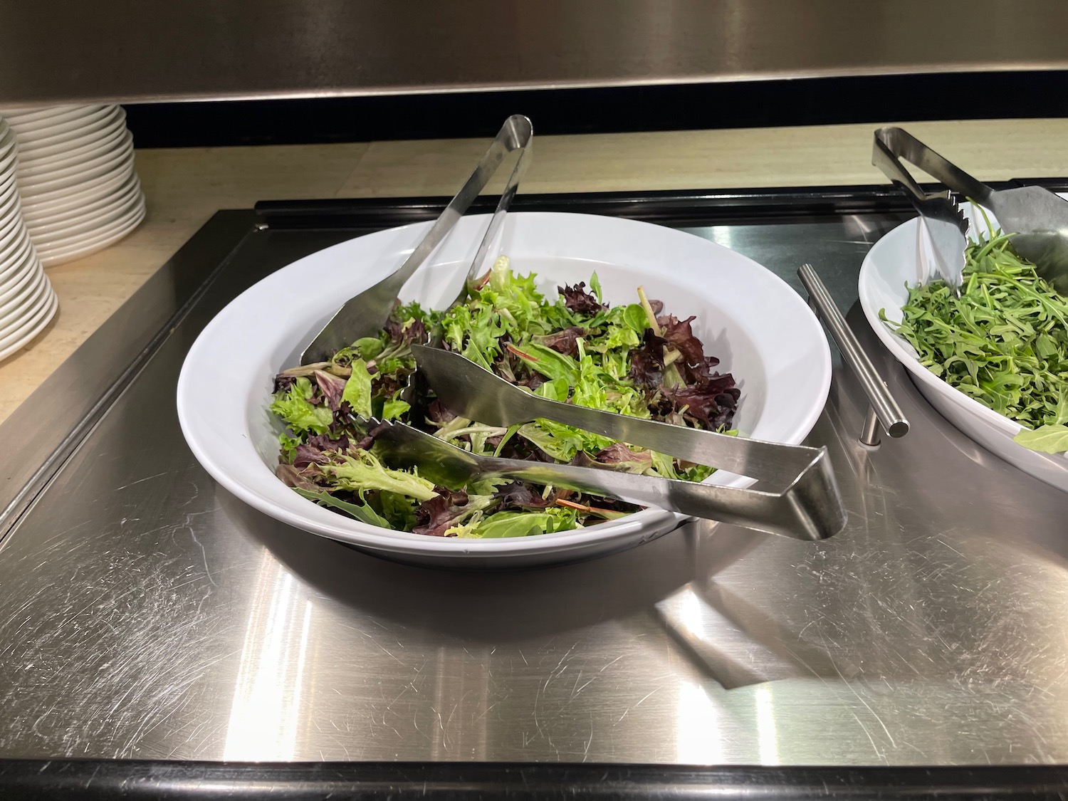 a bowl of salad with tongs