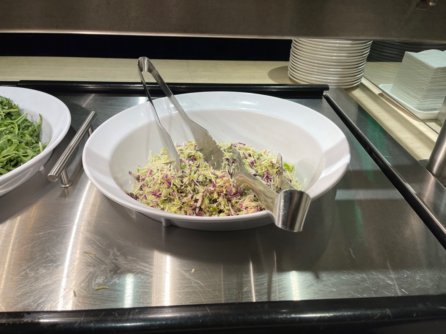 a bowl of salad with tongs