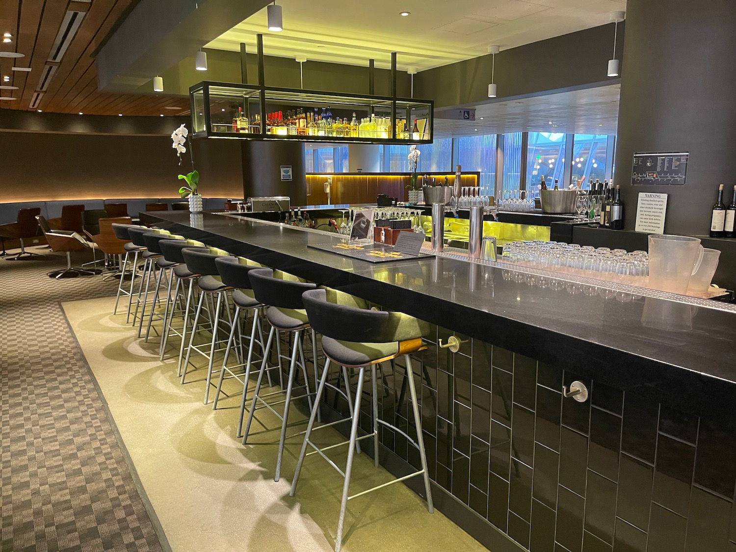 a bar with a row of chairs and a shelf with drinks