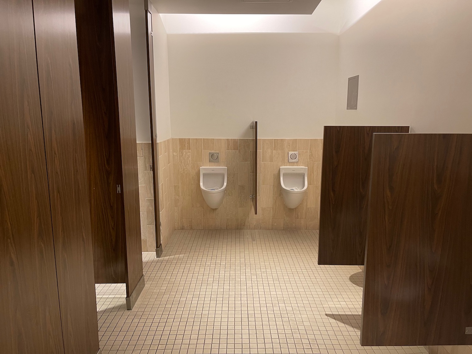 a bathroom with urinals and brown tiles