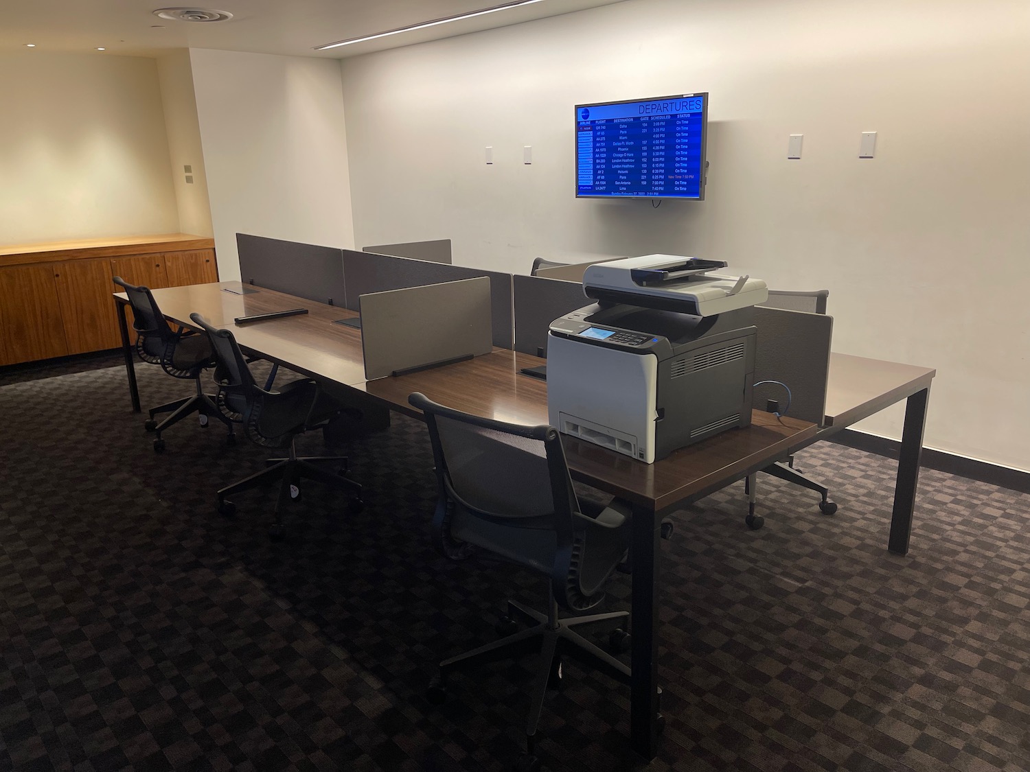a large office table with a printer and chairs