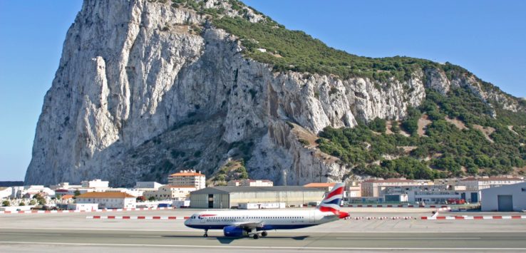 an airplane on a runway with a mountain in the background