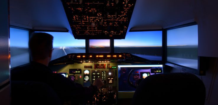 a man in a cockpit with a large screen and a large window