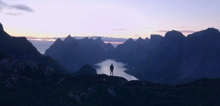 a person standing on a mountain top overlooking a body of water