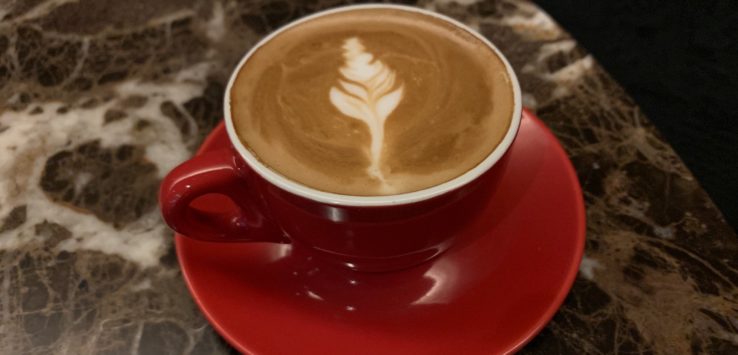 a cup of coffee with a leaf design on top of it