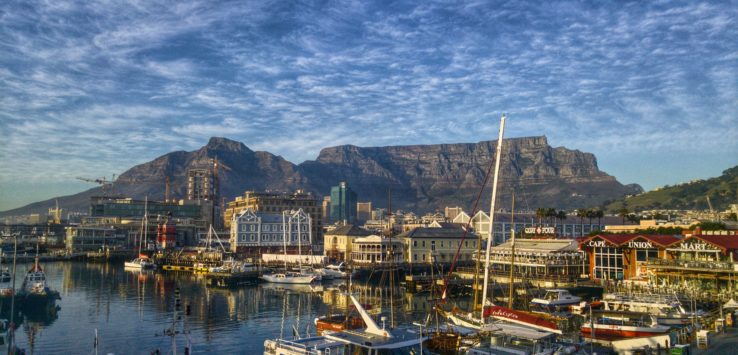 a harbor with boats and mountains in the background with Victoria & Alfred Waterfront in the background