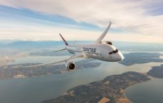 a white airplane flying over water