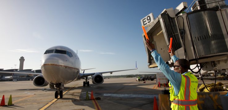 a man in a safety vest standing next to an airplane