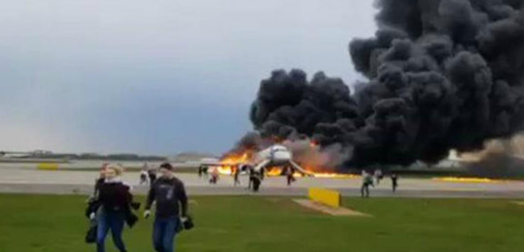 a plane on fire with people walking around