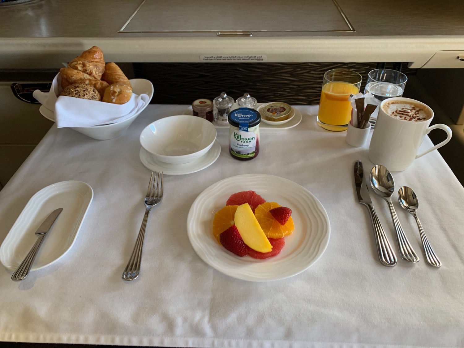 a table with a plate of fruit and a bowl of coffee