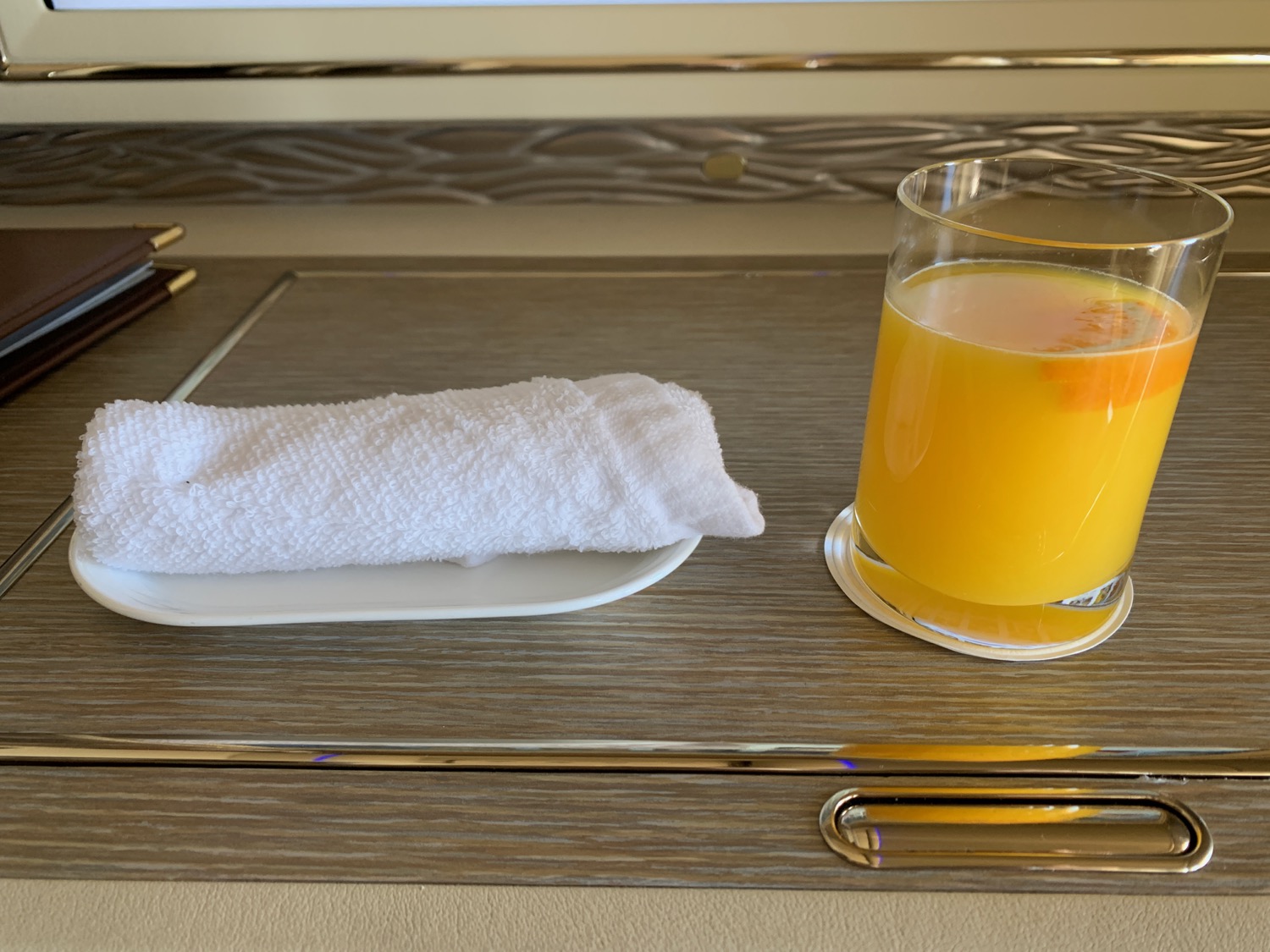 a glass of orange juice and a towel on a tray