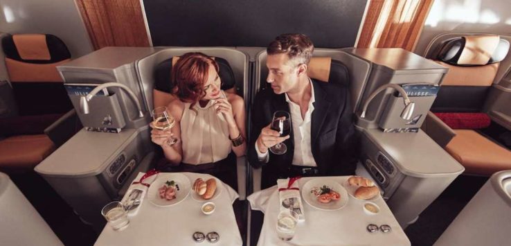 a man and woman sitting in a chair with food and drinks