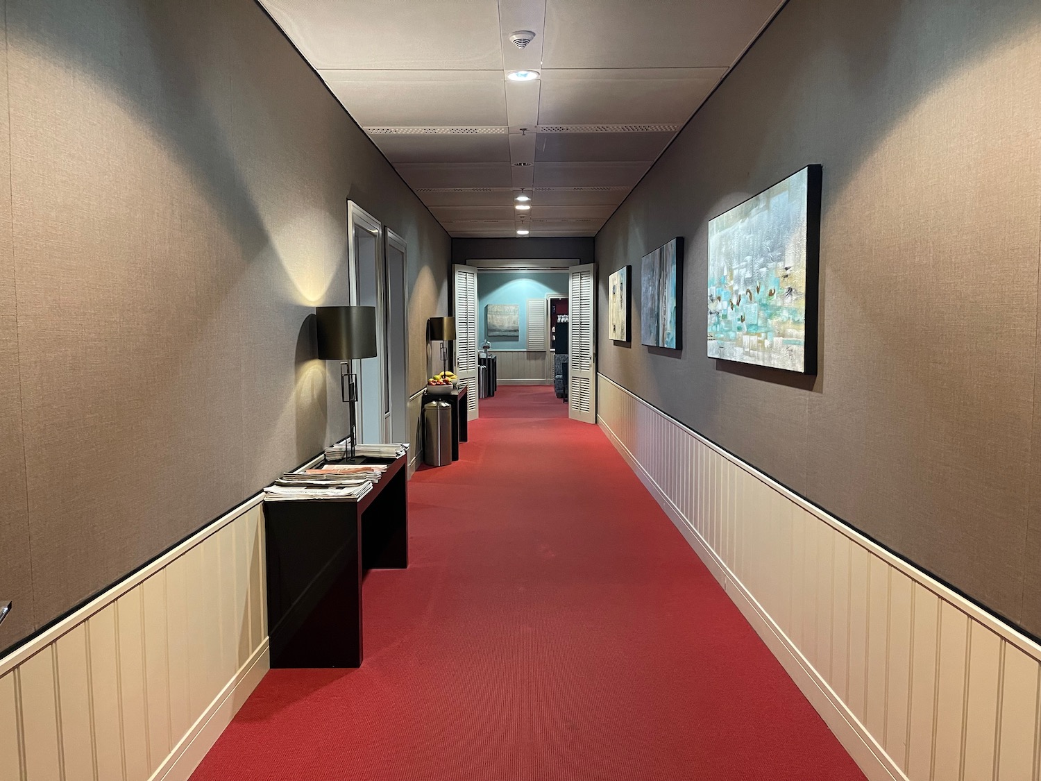 a hallway with red carpet and art on the wall