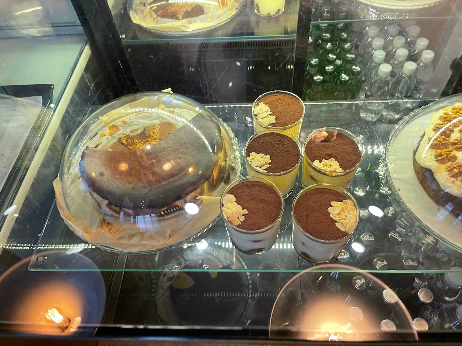 a glass case with desserts and cups on it