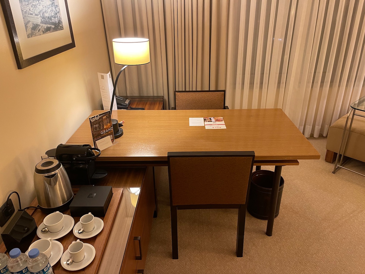 a desk with a lamp and coffee cups on it