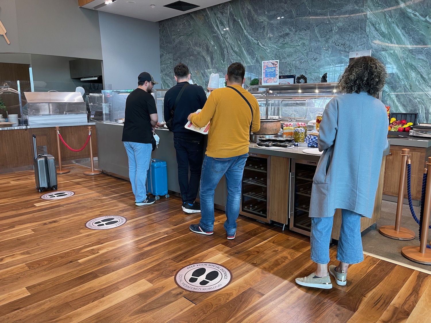 a group of people standing in a line at a food counter