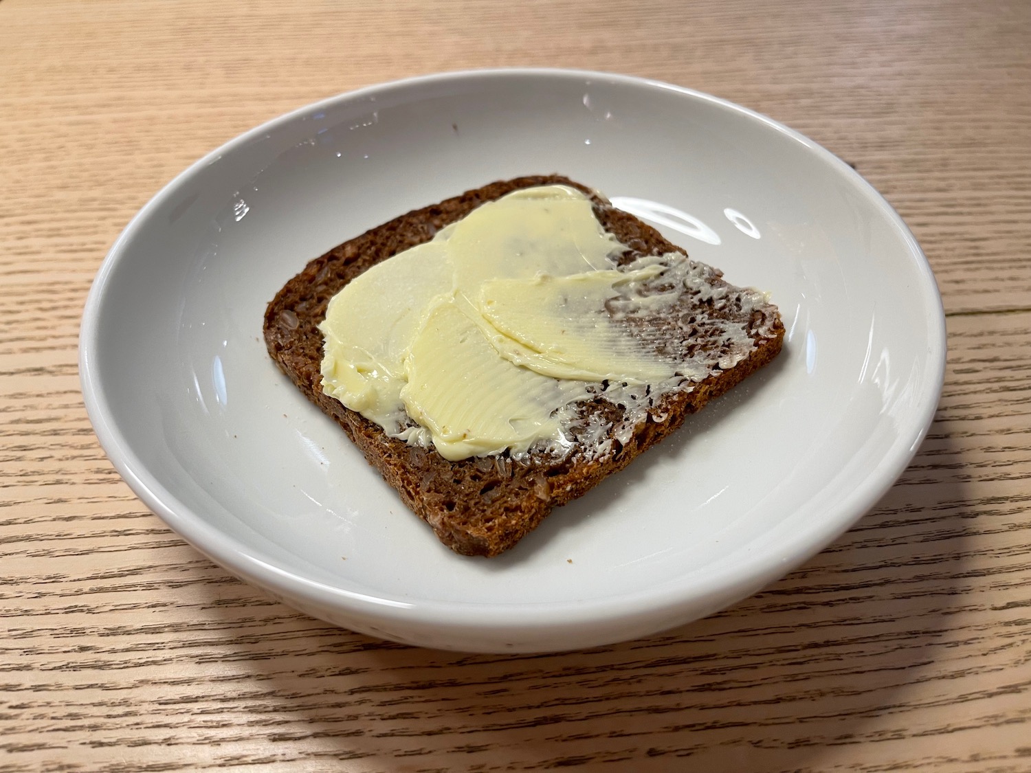 a piece of bread with butter on a white plate