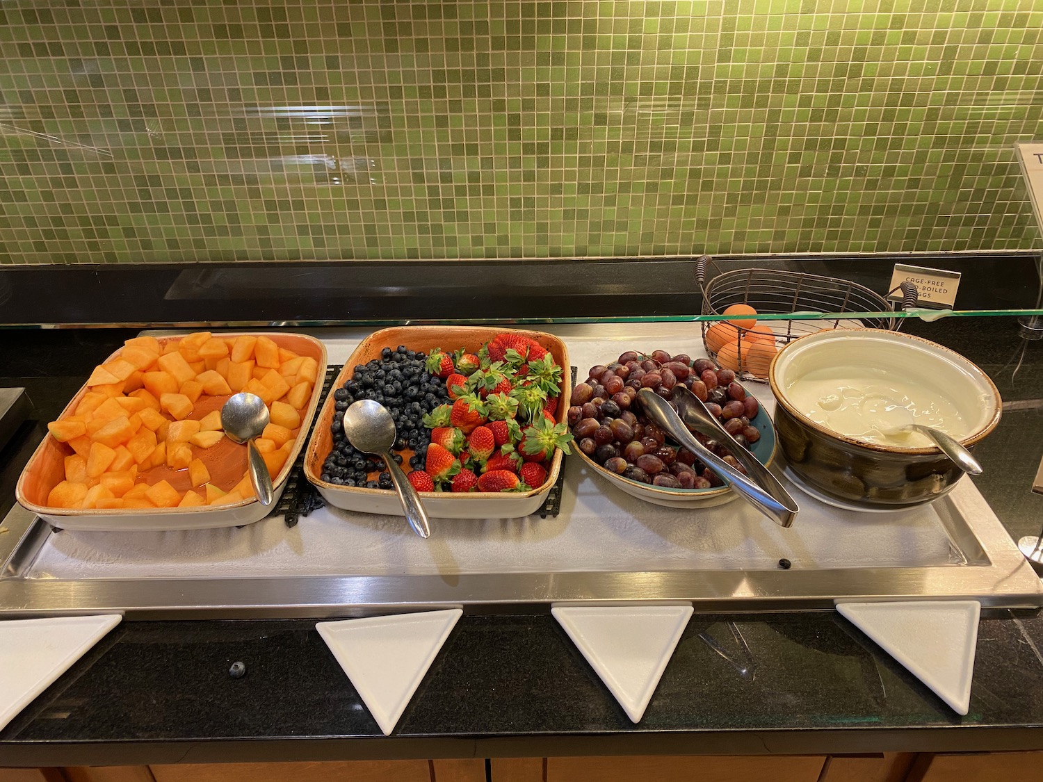 a buffet table with different bowls of fruit and a bowl of yogurt