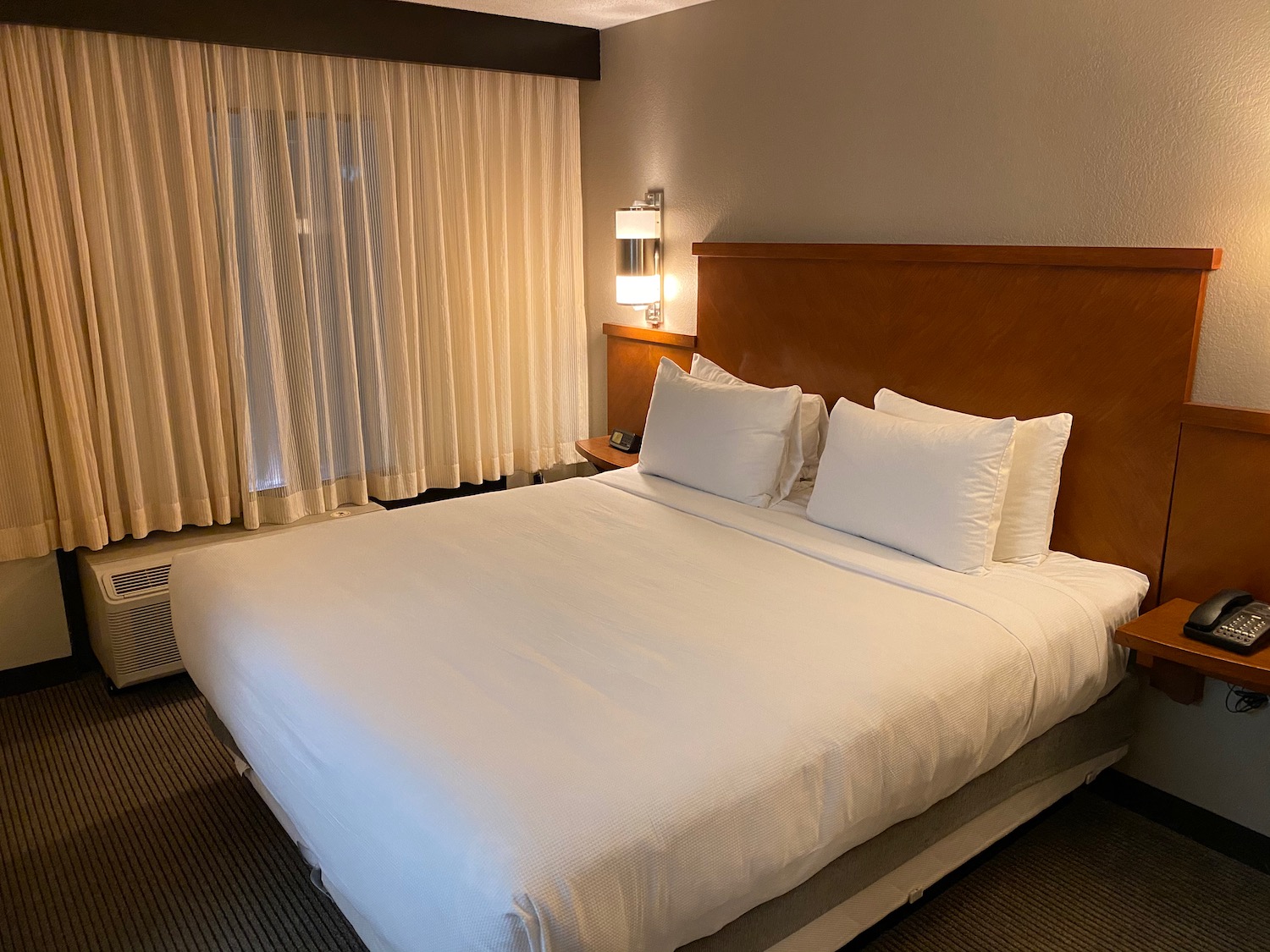 a bed with white sheets and pillows in a hotel room