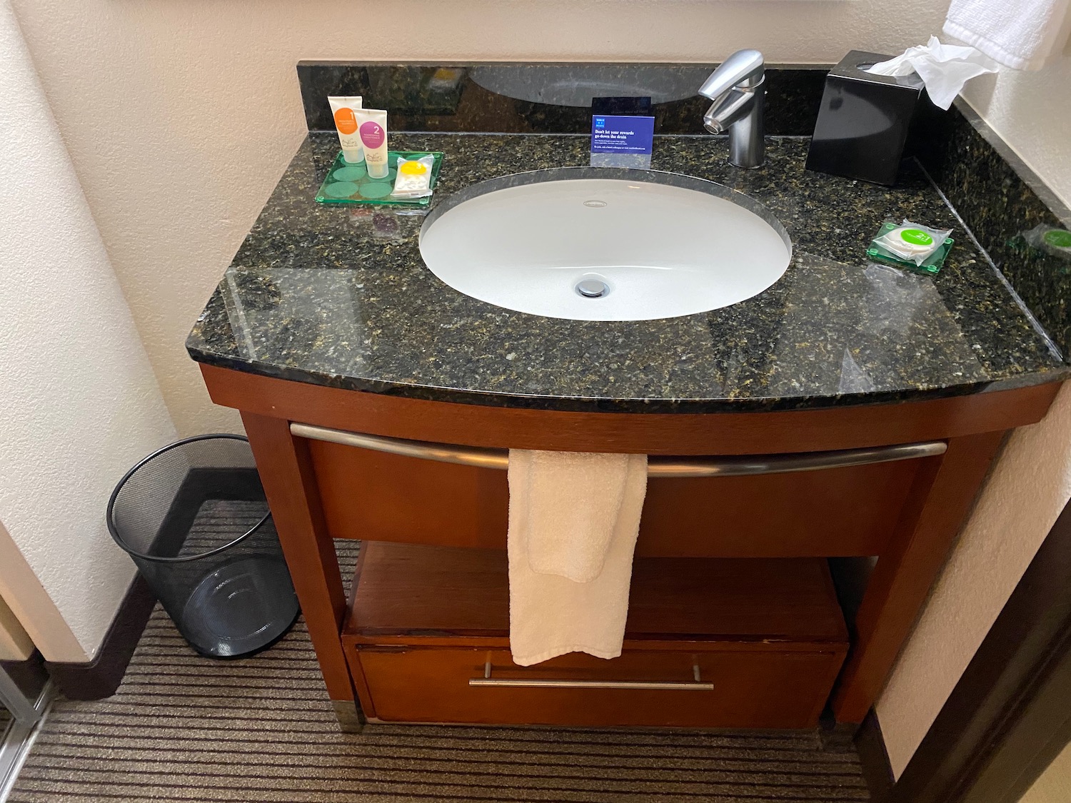 a bathroom sink with a towel and a trash can