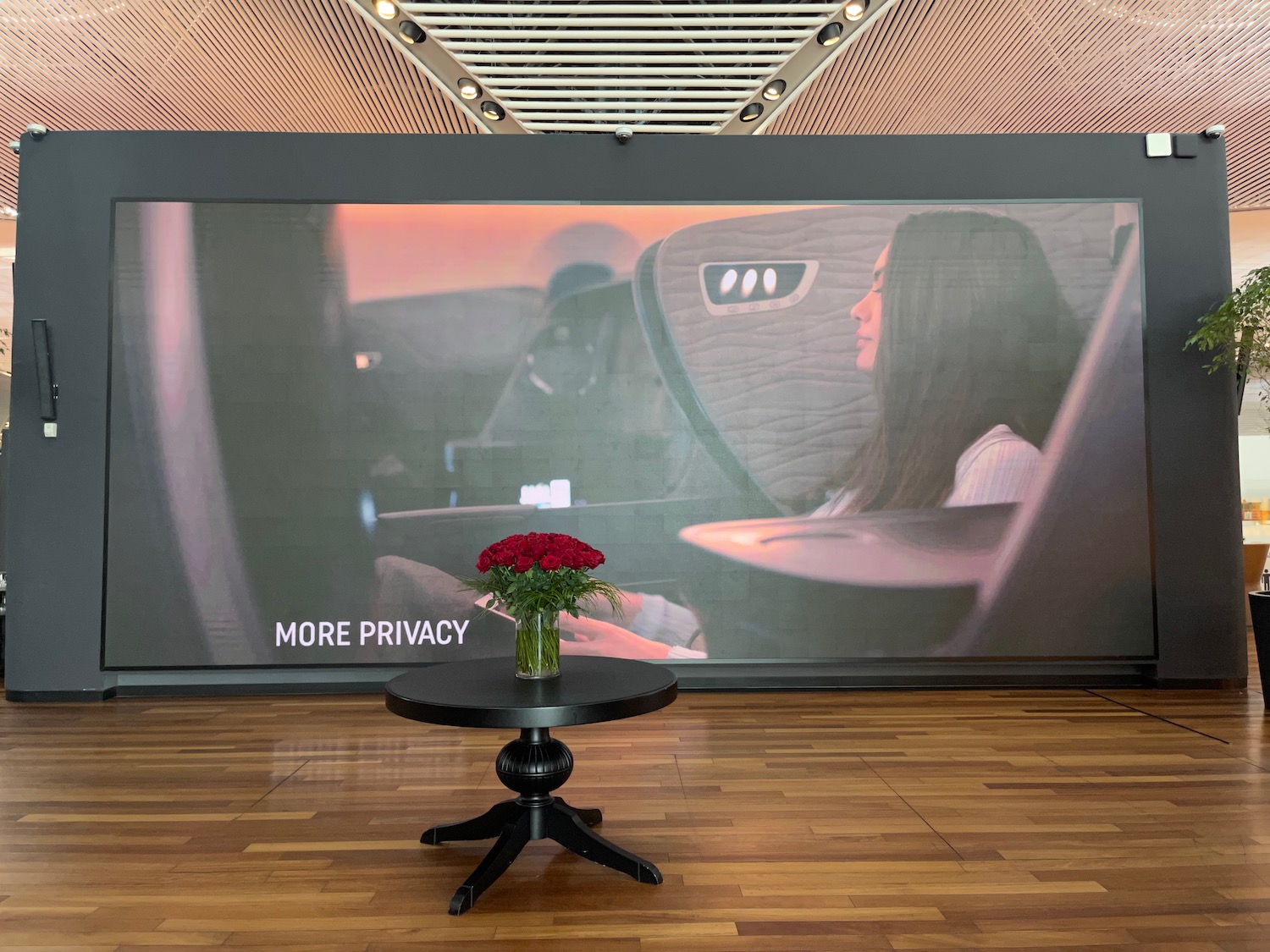 a table with a vase of flowers on it in front of a large screen