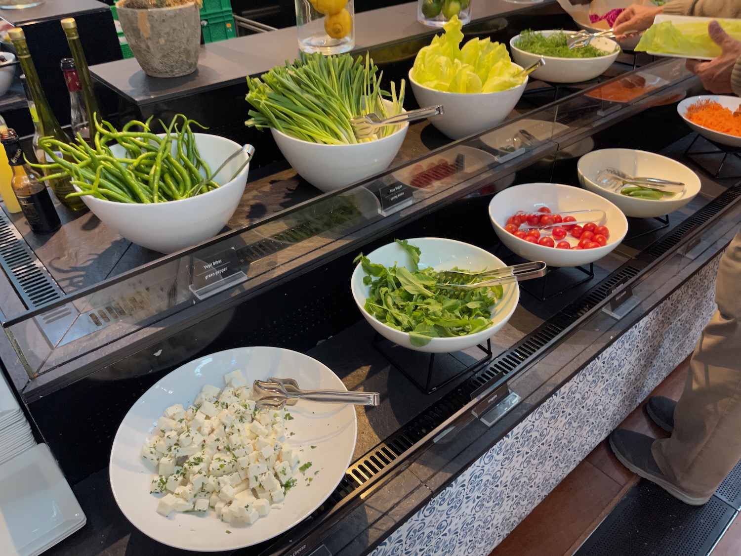 a salad bar with bowls of vegetables and greens