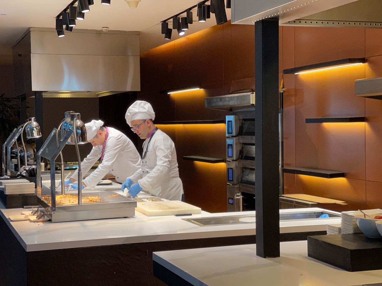 two men in white coats cooking food in a kitchen