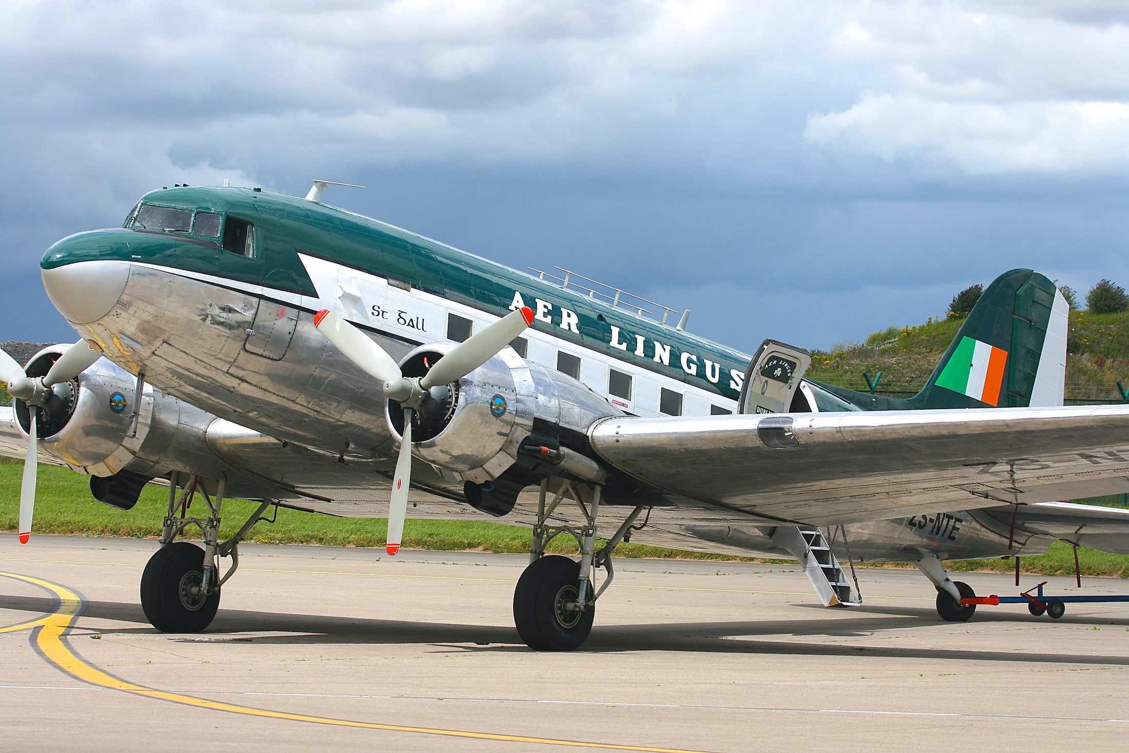 a silver and green airplane on a runway