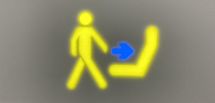 a yellow sign with a blue arrow pointing to a person walking