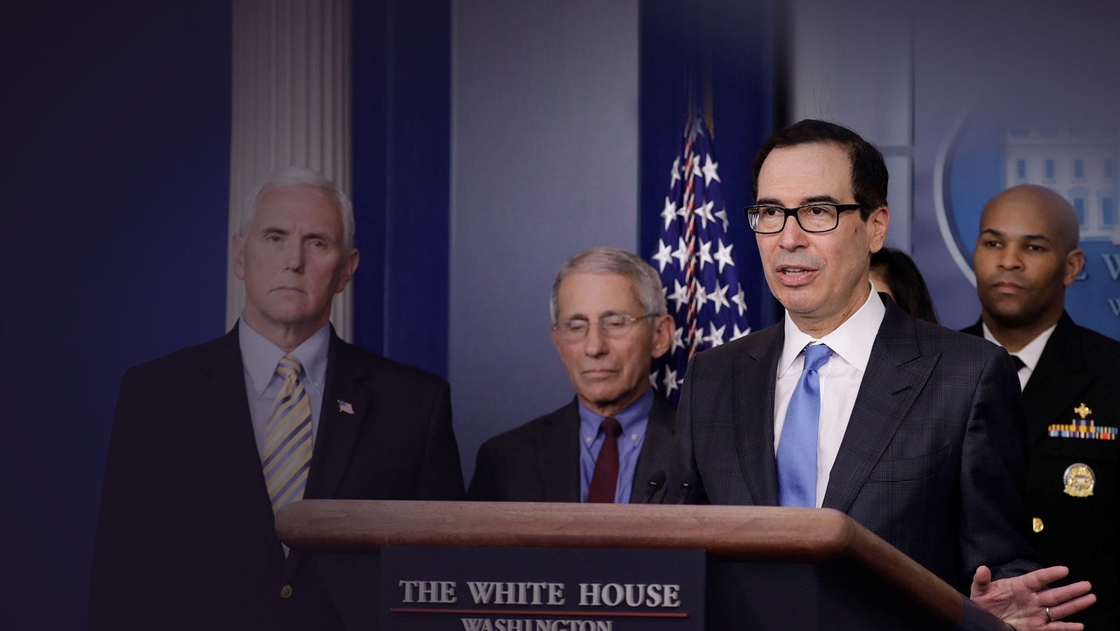 a man in suit and tie standing at a podium with other men in suits