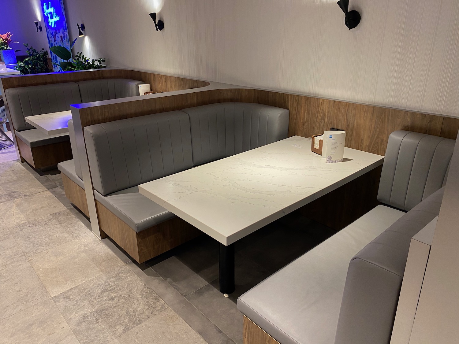 a booth seating with a white table and gray couches