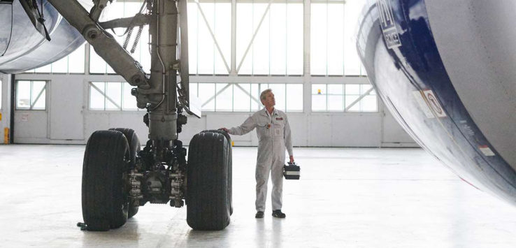 a man in a white jumpsuit standing next to a large airplane