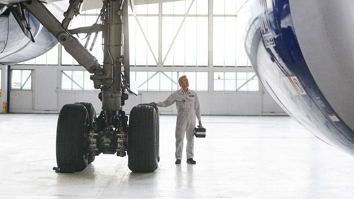 a man in a white jumpsuit standing next to a large airplane