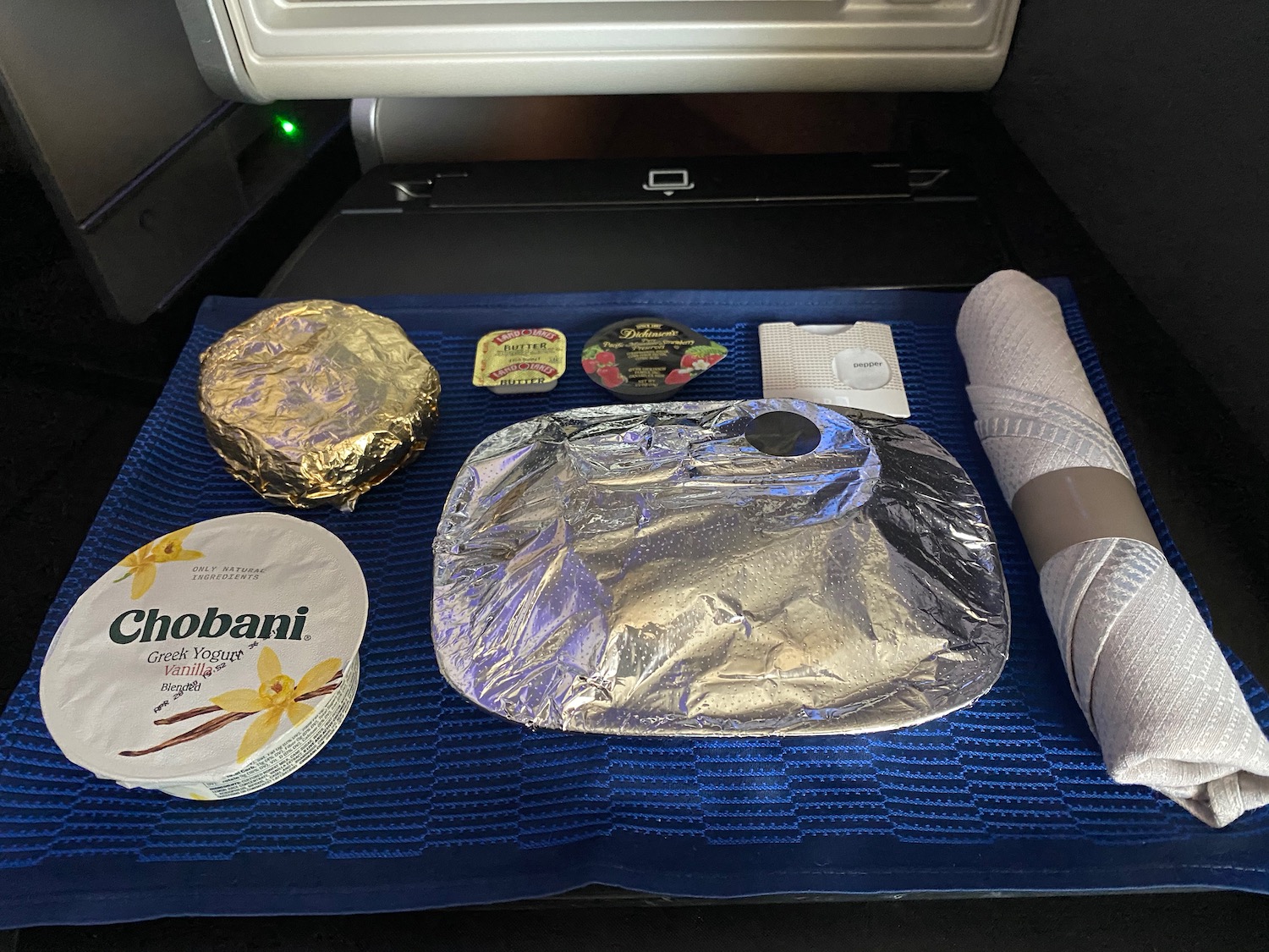 food in a tray with foil and a roll of paper
