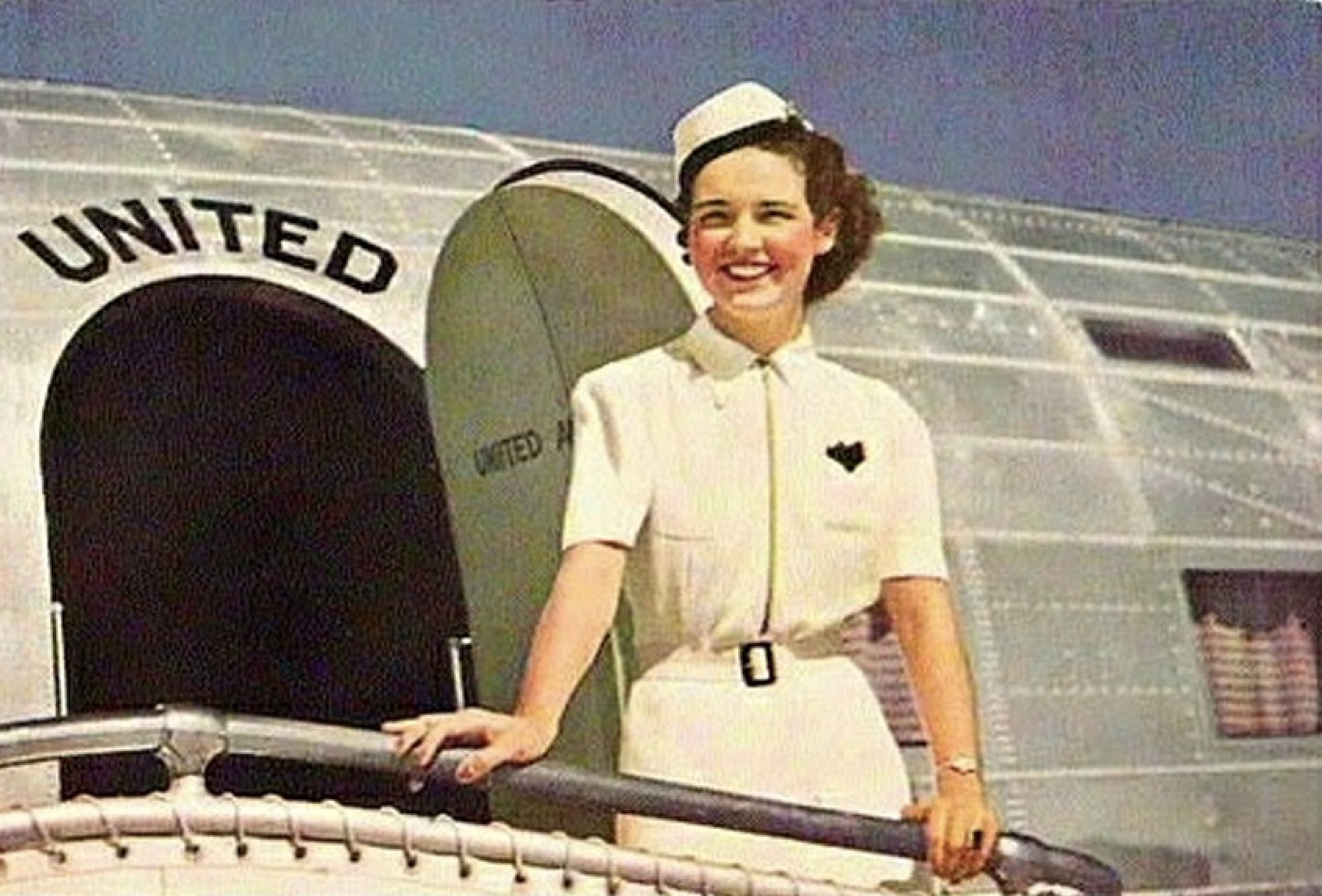 a woman in uniform standing in front of an airplane