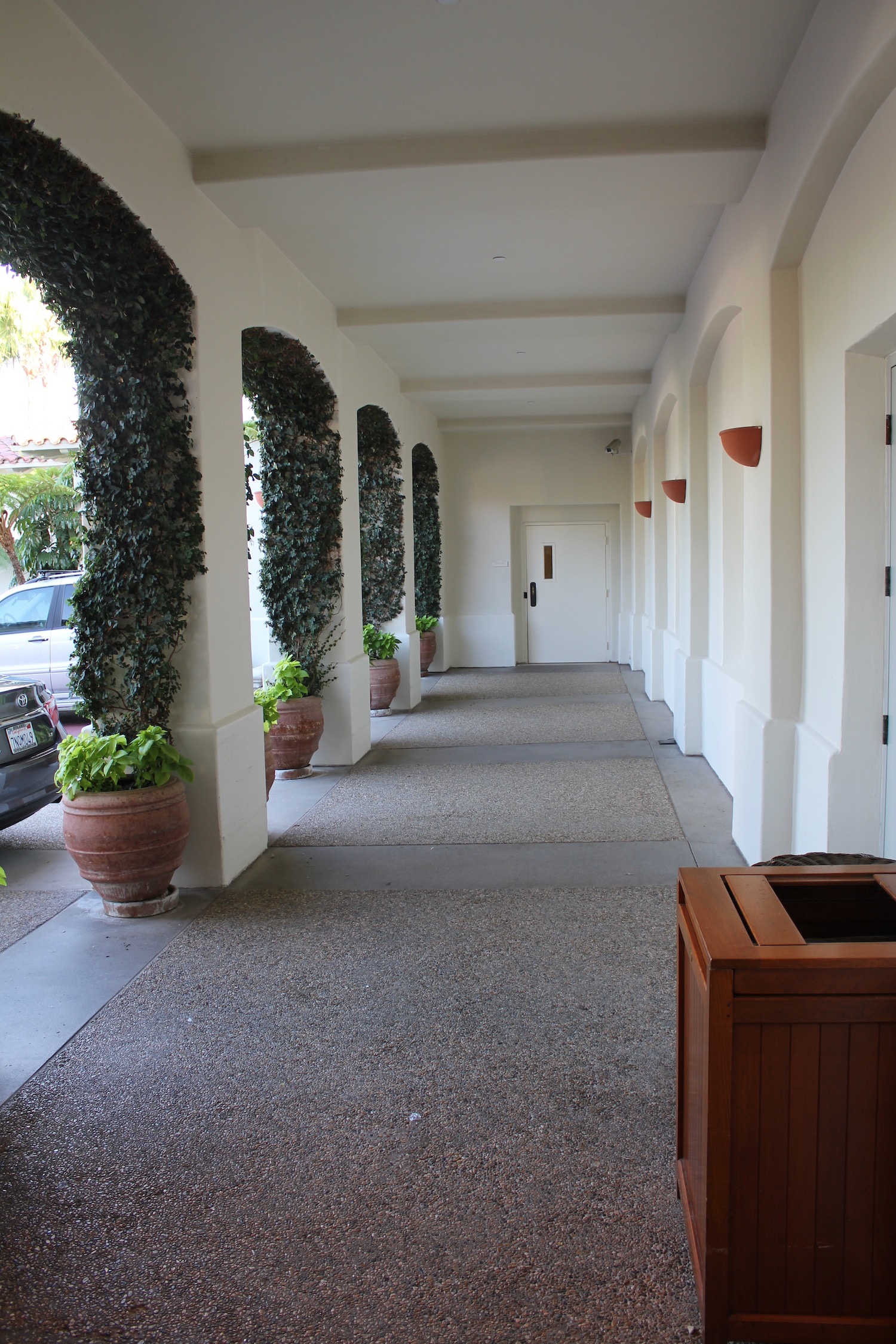 a white building with a white door and a white wall with plants