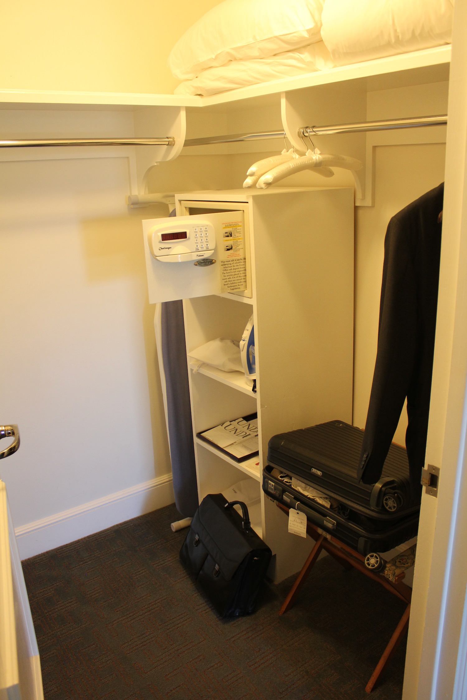 a small white closet with a combination lock and a suitcase