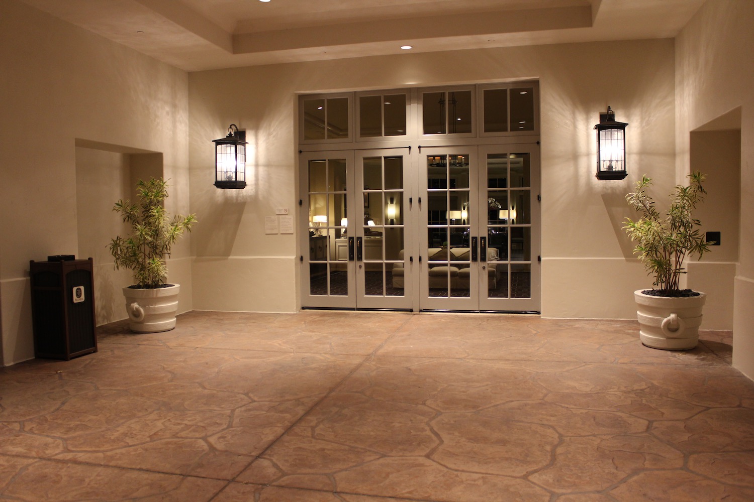 a large room with double doors and plants